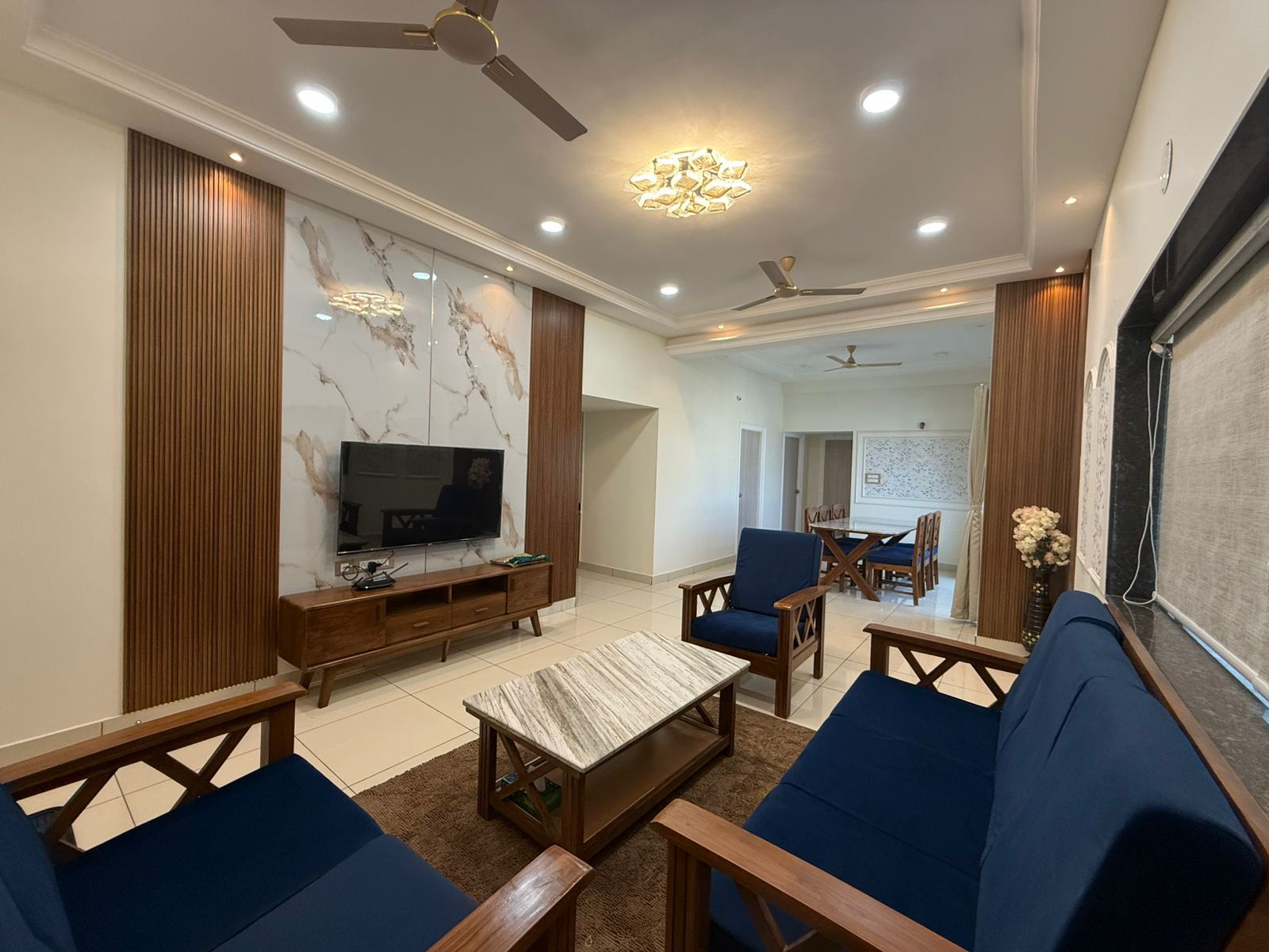 Living room of a Zuza Homes service apartment in Reti Bowli, Mehdipatnam, Hyderabad, with sofa seating, a TV unit and the dining area behind